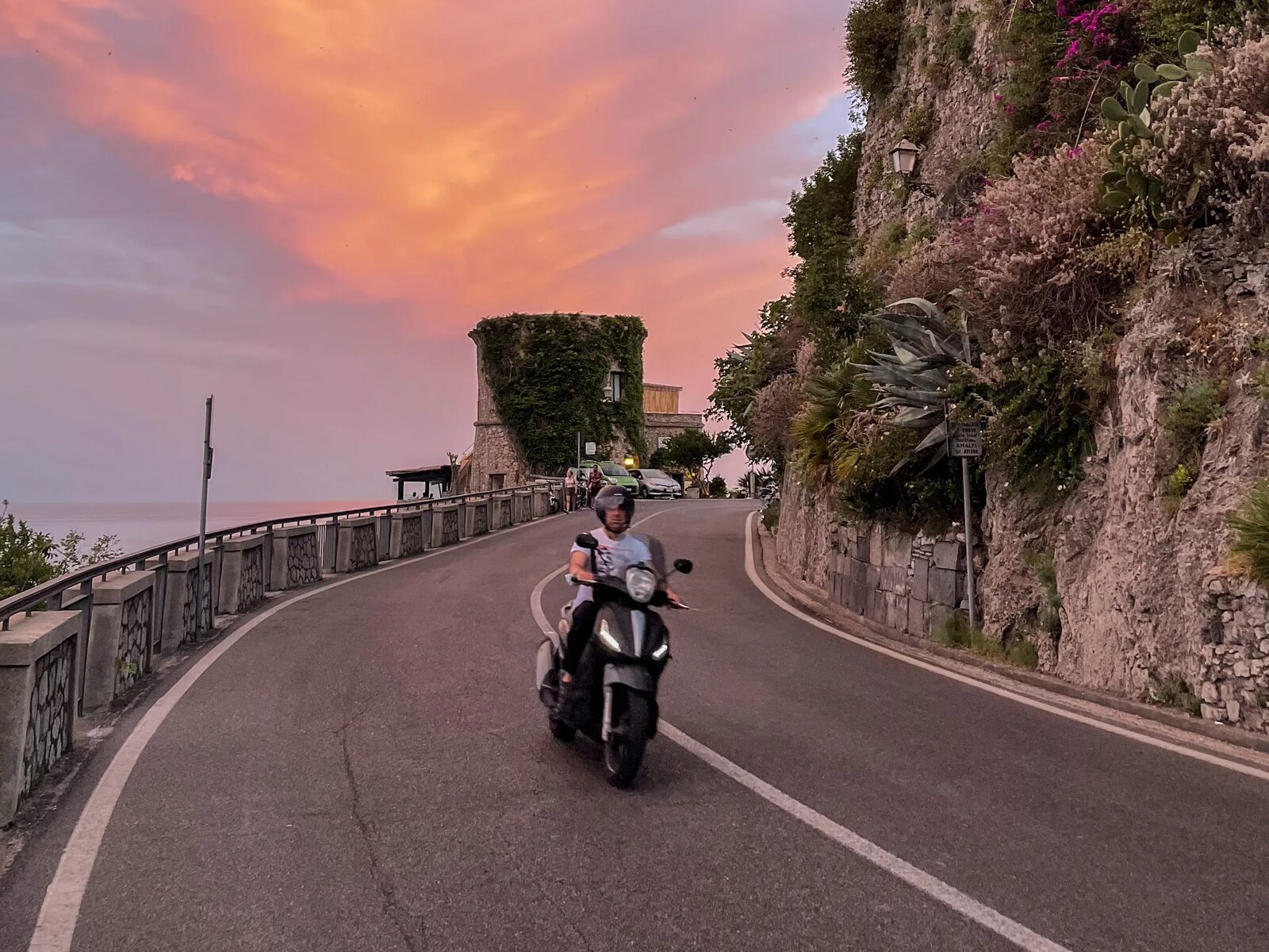 Scooter on an empty coast road at sunset
